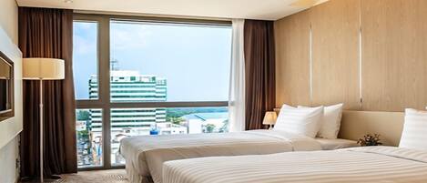 Een hotelkamer met twee bedden, een groot raam en stadszicht, met een modern design.