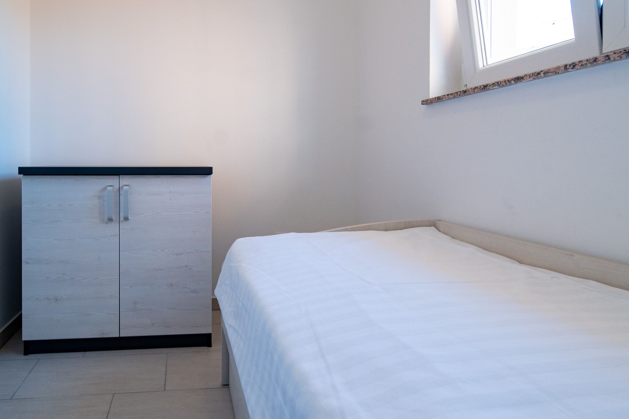A bedroom with a bed, a wardrobe, and a window.
