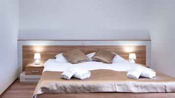 A bedroom with a wooden bed, white bedding, two bedside tables with lamps, and a ceiling light.
