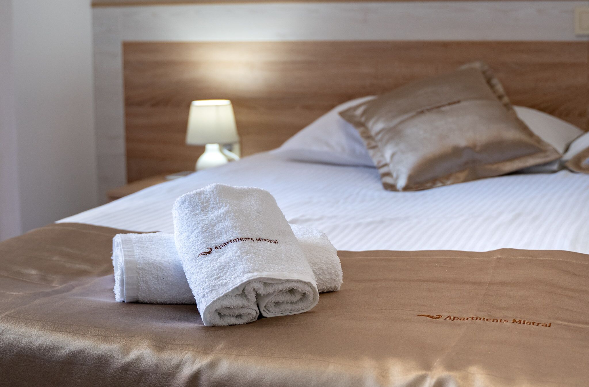 Ein ordentlich bezogenes Bett mit einem weißen Handtuch und einem Kissen auf einer braunen Bettdecke.