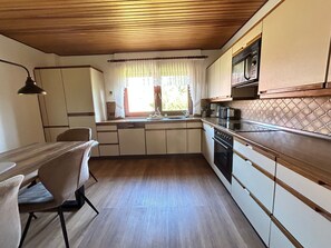 A kitchen with wooden cabinets, a sink, a stove, and a dining area with a table and chairs.