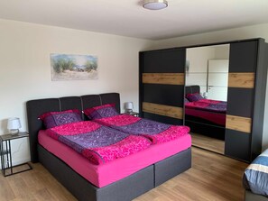 Un dormitorio moderno con una cama, mesitas de noche, un espejo y un cuadro en la pared.