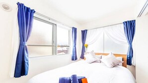 A hotel room with a bed, white curtains, and a window with a view. - Eve (Sapporo)