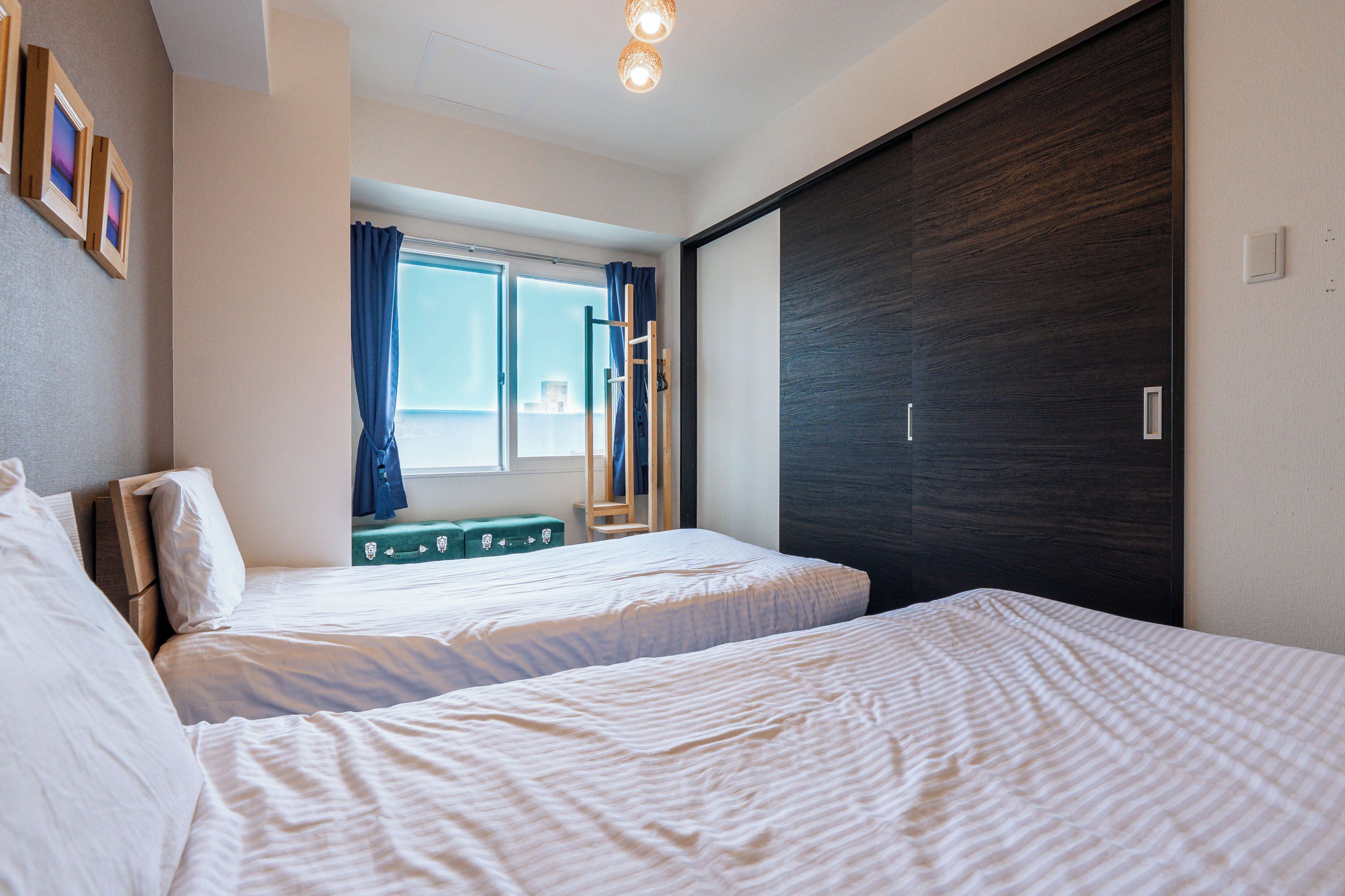 Un dormitorio con dos camas, una ventana con cortinas y un armario de madera oscura.