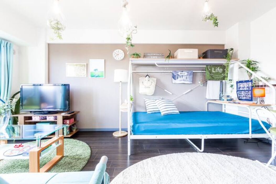 A compact living space with a bunk bed, a television, and a small desk area.