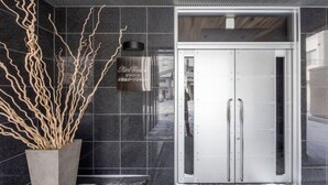 Una entrada de hotel moderna con una planta grande en maceta y un cartel sobre la puerta.