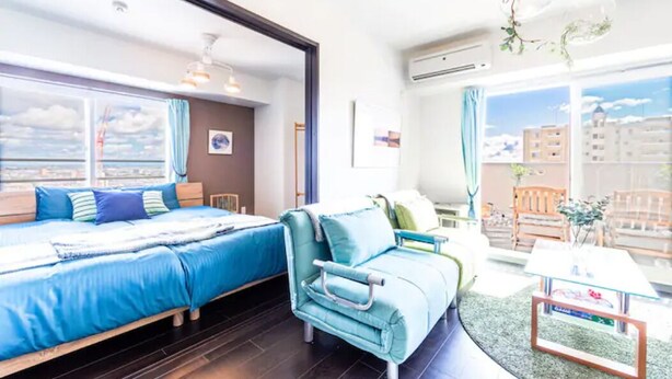 Una habitación de hotel moderna con una cama grande, un sofá azul y una pequeña mesa.