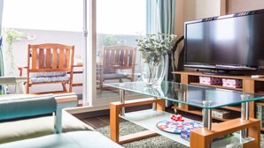 Una sala de estar con una mesa de centro de vidrio, un televisor y una silla de madera.