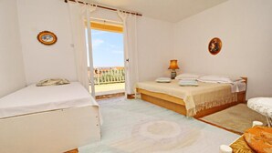 A bedroom with two beds, a balcony, and a small table with a lamp. - Apartment Pehar (Orebic)