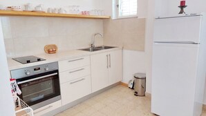 A kitchen with white cabinets, a stainless steel sink, a built-in oven, and a white refrigerator. - Apartment Pehar (Orebic)