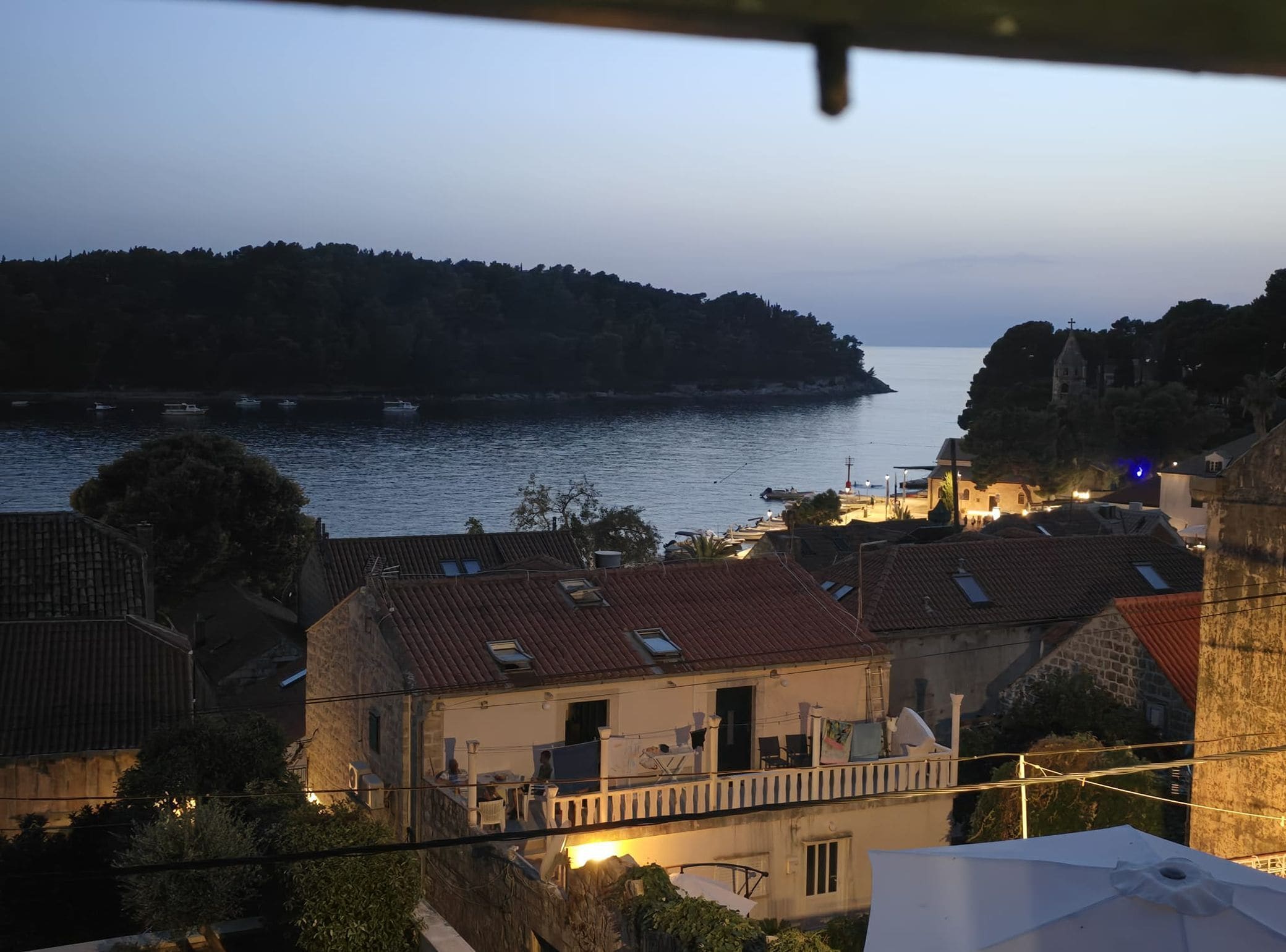 Ein Küstendorf mit Steinhäusern, Blick auf das Meer und einer Kirche mit einem Glockenturm.