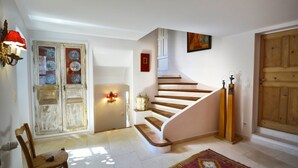 A staircase with wooden steps leading to a landing, a rustic door with glass panels, a wall-mounted light fixture, and a patterned rug on the floor. - Séguret, cosy village house with exceptional view (Seguret)