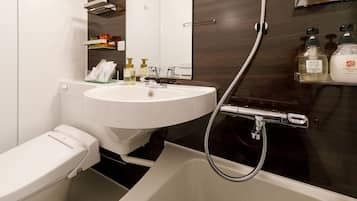 A modern bathroom with a white sink, toilet, and bathtub. There are toiletries on the sink and a shower head above the bathtub.