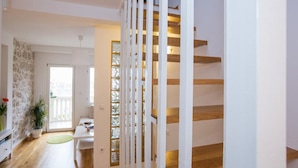 Un interior moderno con una escalera, una zona de comedor y vistas al exterior.