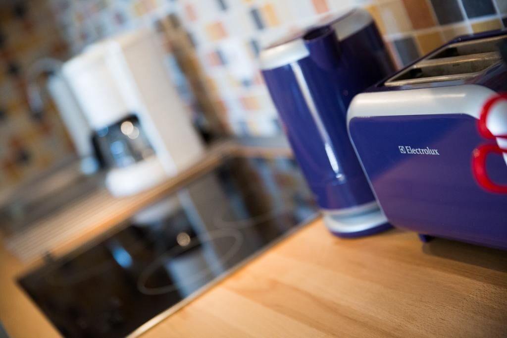 Una encimera de cocina con una cafetera, un tostador y un electrodoméstico azul con el logotipo de Electrolux.