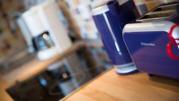 Una encimera de cocina con una cafetera, un tostador y un electrodoméstico azul con el logotipo de Electrolux.