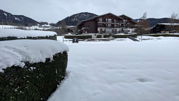 A multi-story building with balconies, surrounded by snow-covered landscape and mountains in the background. - Cozy Garden-Level Studio Cabin in Praz-sur-Arly - Sleeps 4 (Praz-sur-Arly)