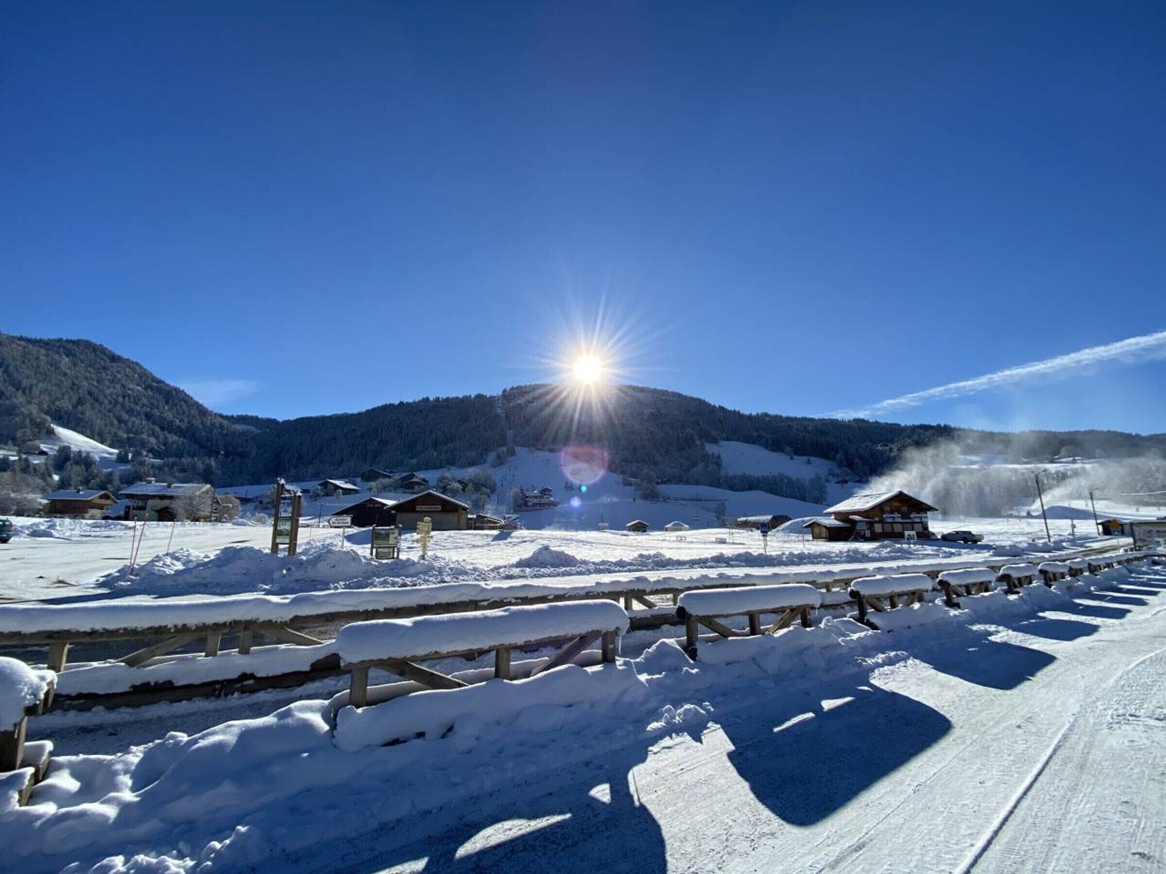 A snow-covered outdoor area with wooden benches and a wooden fence.