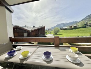 Eine Holzterrasse mit Essplatz, mit Blick auf eine Berglandschaft und traditionelle Bauten.