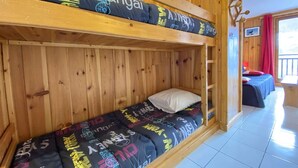 A bunk bed room with wooden walls and a window with red curtains. - Studio cabin, pets welcome - 4 guests, views of ski slopes (Praz-sur-Arly)