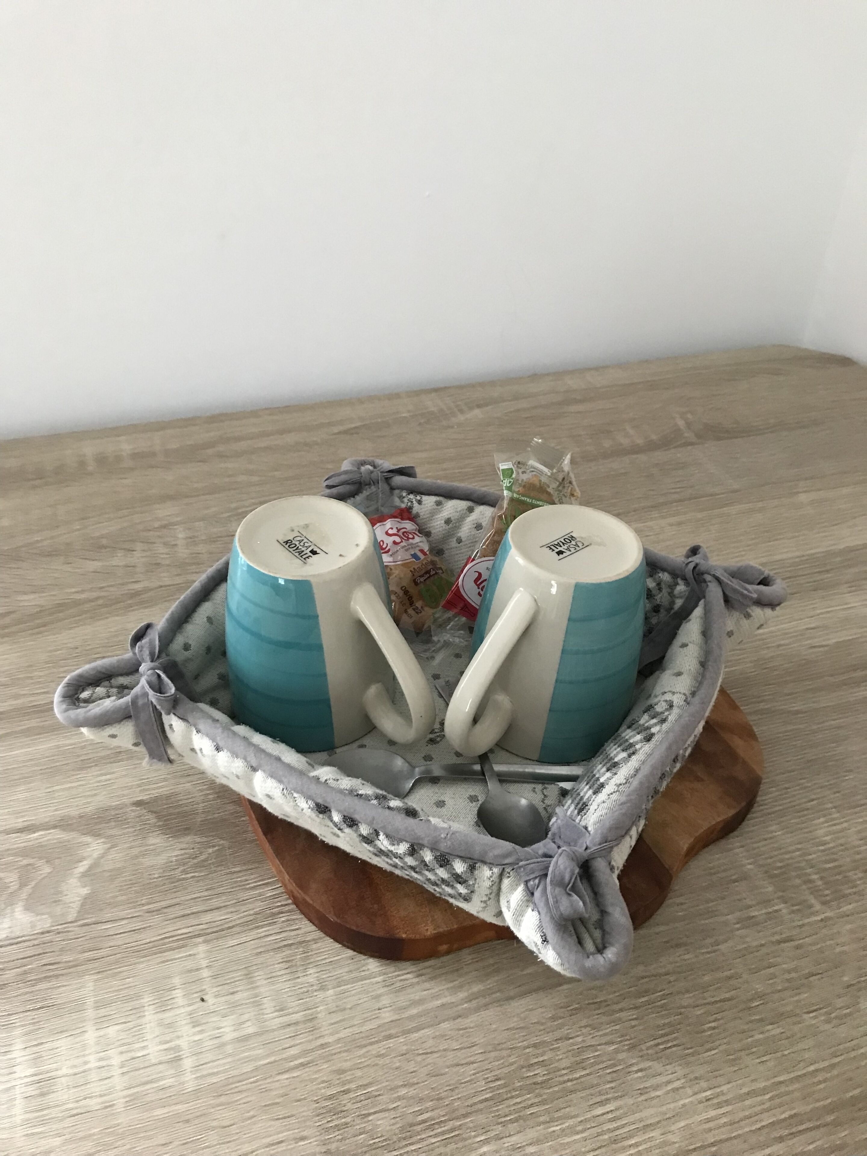 Two mugs with handles, placed on a wooden tray with a cloth.