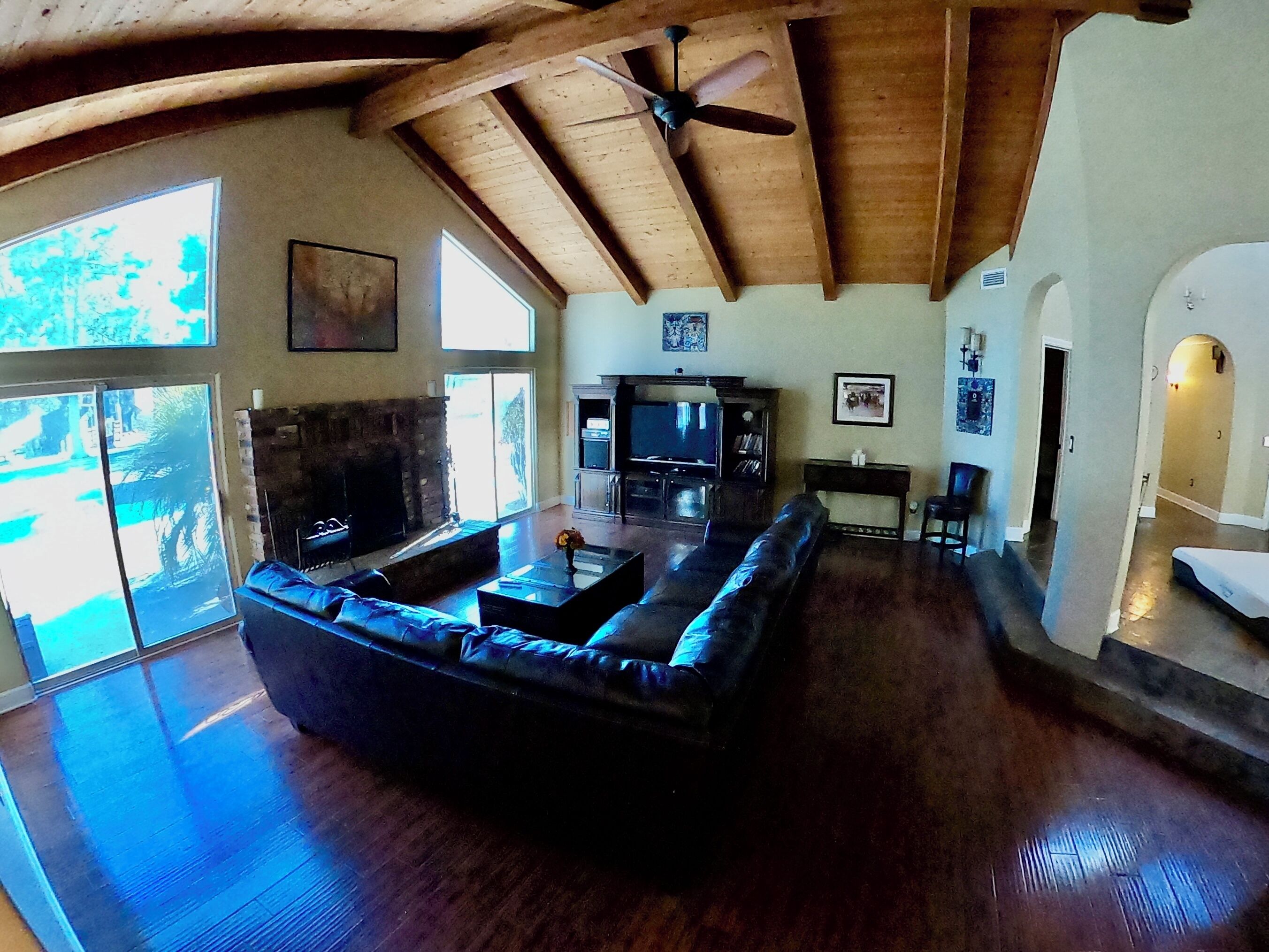 A spacious living room with a large sectional sofa, a fireplace, and a ceiling fan.