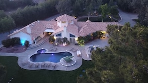 A large house with a swimming pool, multiple outdoor seating areas, and a well-maintained garden.