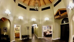 A spacious interior with a high ceiling, multiple arches, and a central hallway leading to bedrooms.