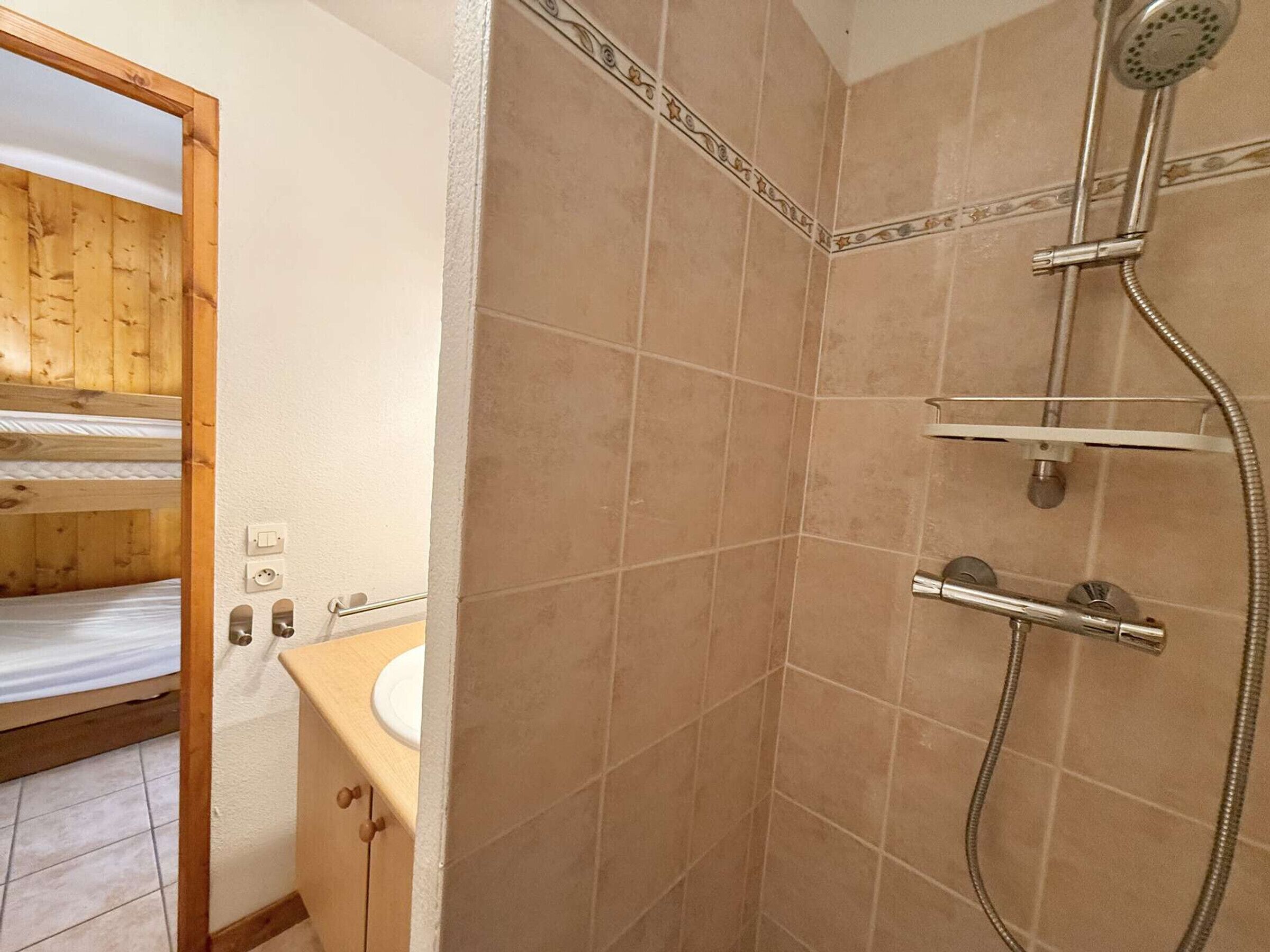 A bathroom with a shower, a wooden bunk bed, and a sink.