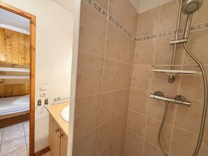 A bathroom with a shower, a wooden bunk bed, and a sink.