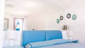 Een slaapkamer met een bed, twee nachtkastjes, een spiegel en decoratie aan de muur.