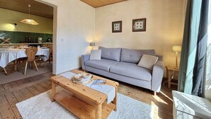 A cozy living room with a grey sofa, wooden coffee table, and a dining area in the background. - Cozy apartment in Praz-sur-Arly, 2 rooms, near village (Praz-sur-Arly)