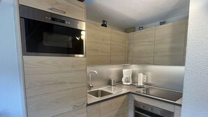 Uma cozinha compacta com forno embutido, cafeteira e pia.