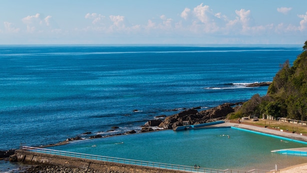 A coastal swimming pool with clear blue water, surrounded by rocky terrain and a beach. - Oceanic 3 - On The Beach! (Forster)