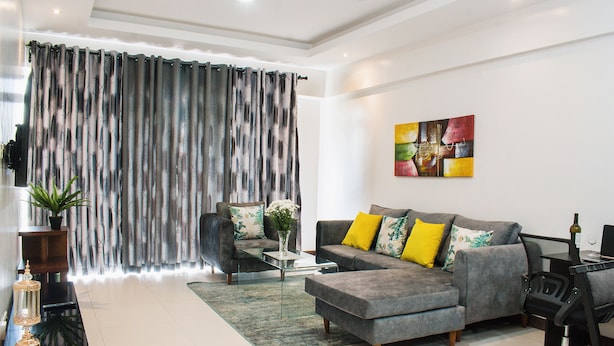 Una sala de estar moderna con un sofá gris, una mesa de centro y una silla de oficina negra.
