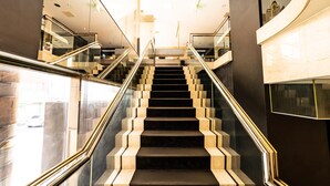 Una escalera moderna con barandillas de vidrio y diseño geométrico, que conduce a un piso superior.