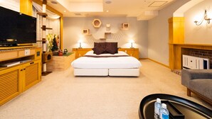 Una habitación de hotel con una cama grande, televisión, chimenea y sofá.