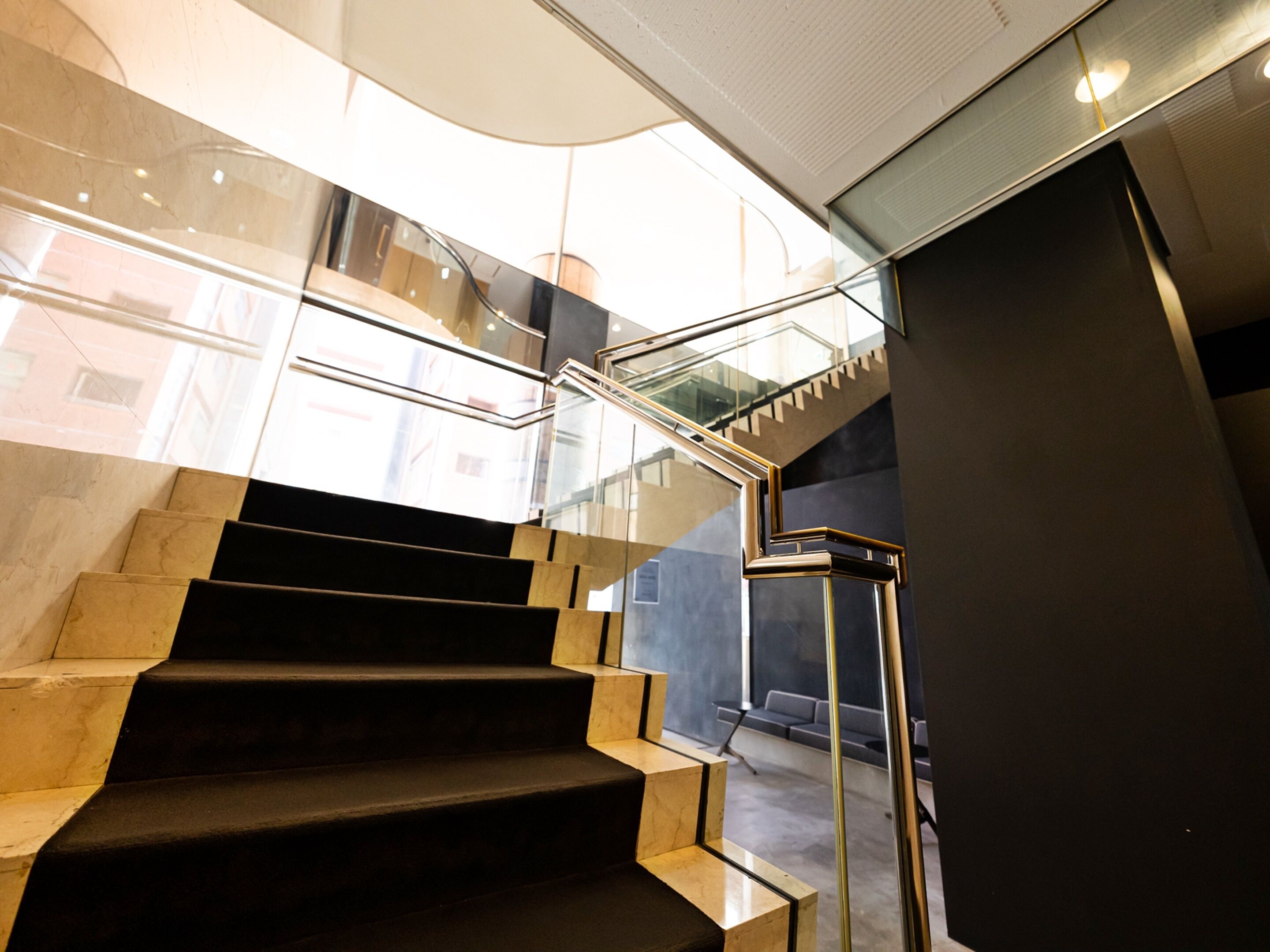 A modern staircase with glass railings and a curved ceiling.