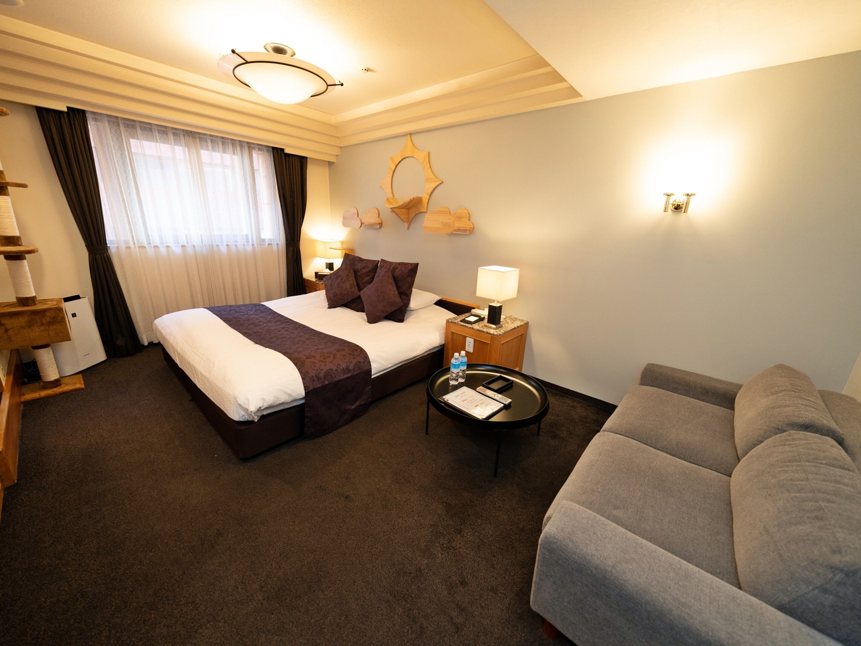 A hotel room with a bed, a sofa, a desk, and a lamp.