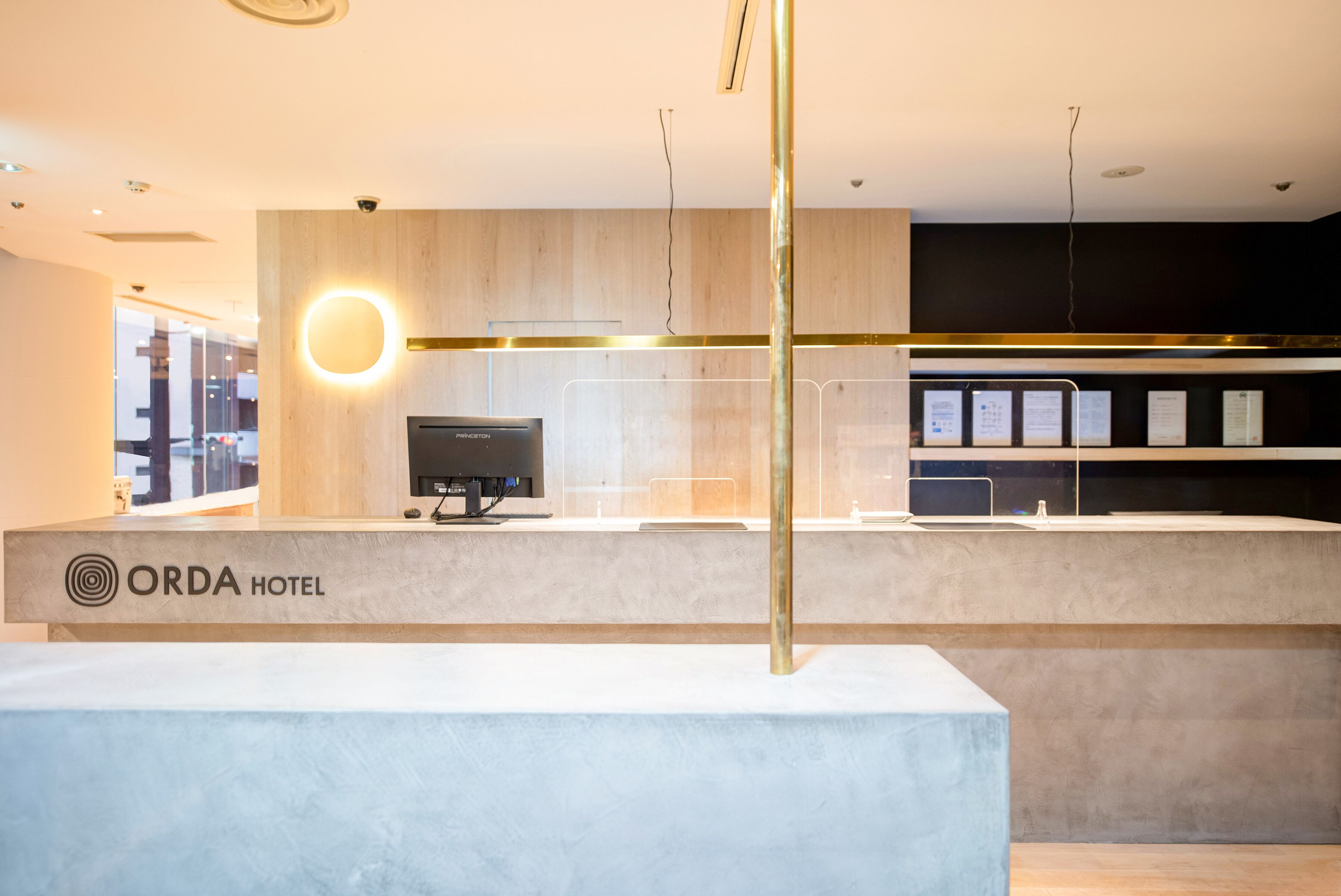 Een receptiebalie met een modern design, een monitor en een bord met de tekst 'ORDA HOTEL'.
