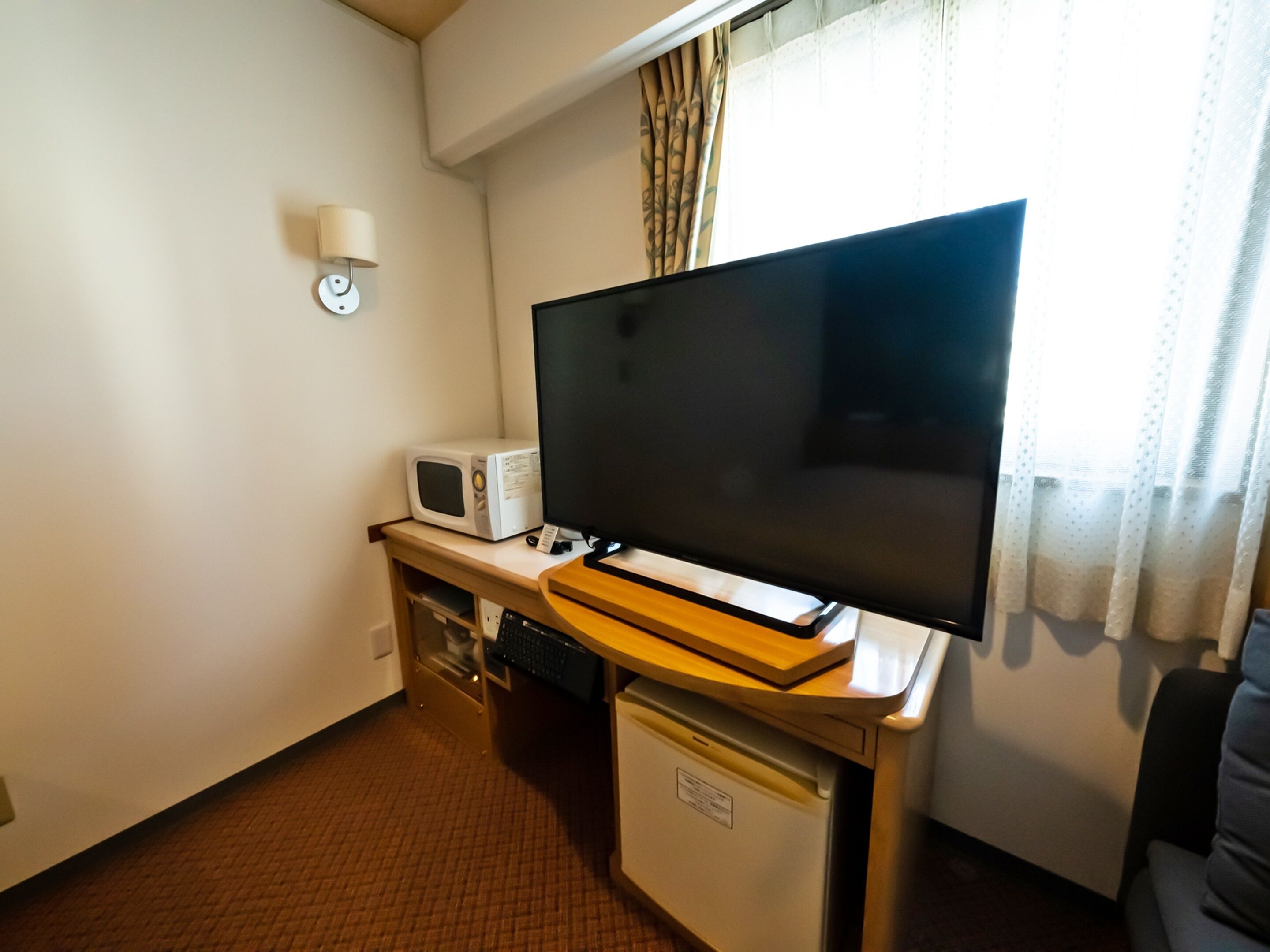 A compact room with a flat-screen TV, a microwave, and a small refrigerator.