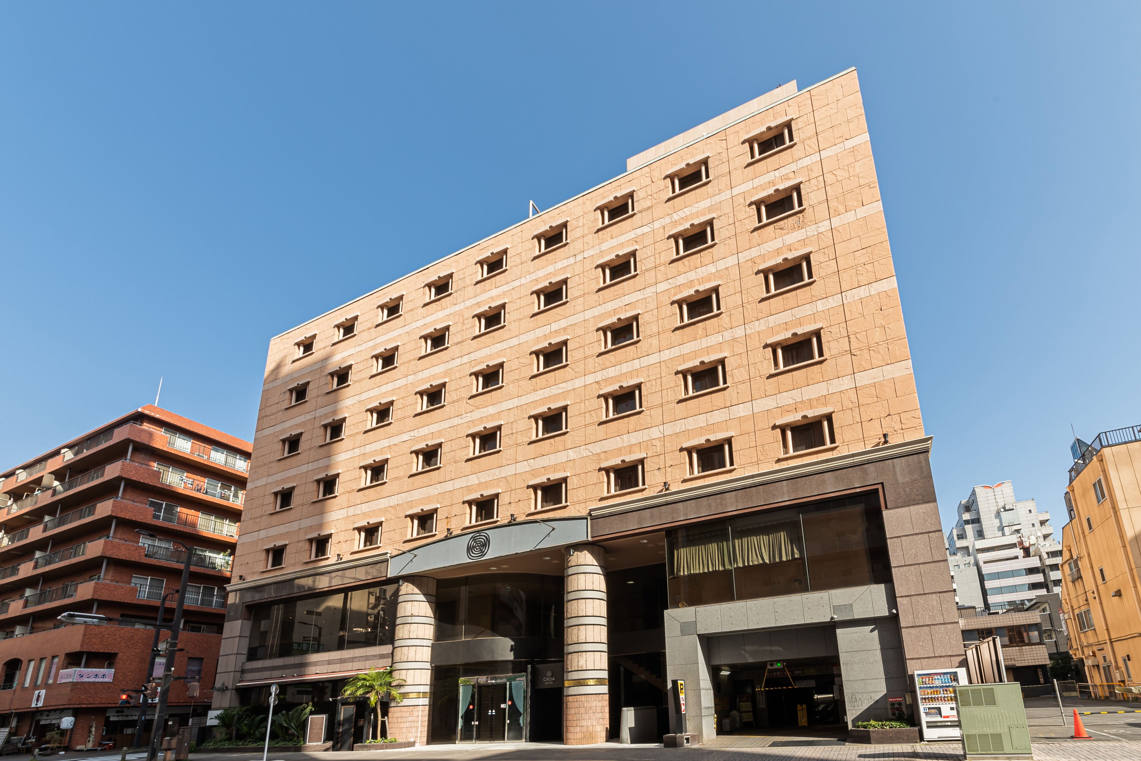 Un hotel de varios pisos con un diseño moderno, que cuenta con una entrada destacada con pilares grandes y fachada de vidrio.