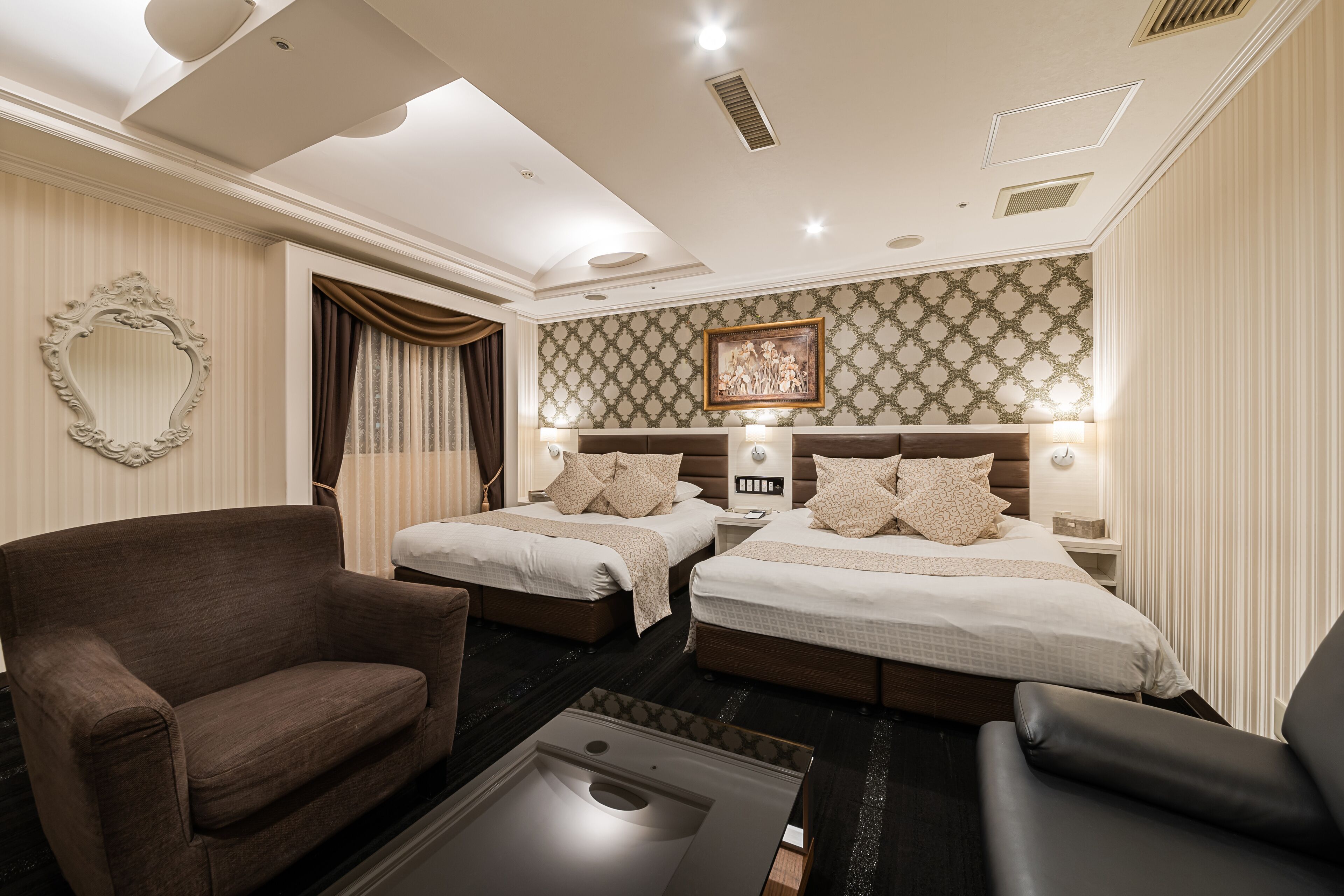A hotel room with two beds, a sofa, a coffee table, and a large mirror.