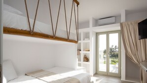 Une chambre avec un lit, un fauteuil suspendu, une étagère intégrée et une porte-fenêtre coulissante donnant sur un balcon.