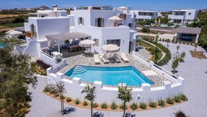Une villa moderne, blanche, dotée d’une piscine, d’un espace salon extérieur et offrant une vue sur la mer.