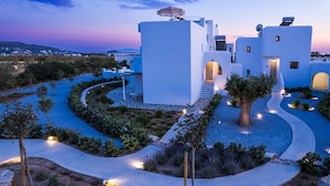 Un bâtiment moderne de couleur blanche, doté d’un chemin sinueux, d’un arbre et offrant une vue sur le paysage.