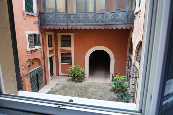 A courtyard with a small archway, a gate, and a balcony with decorative railings.