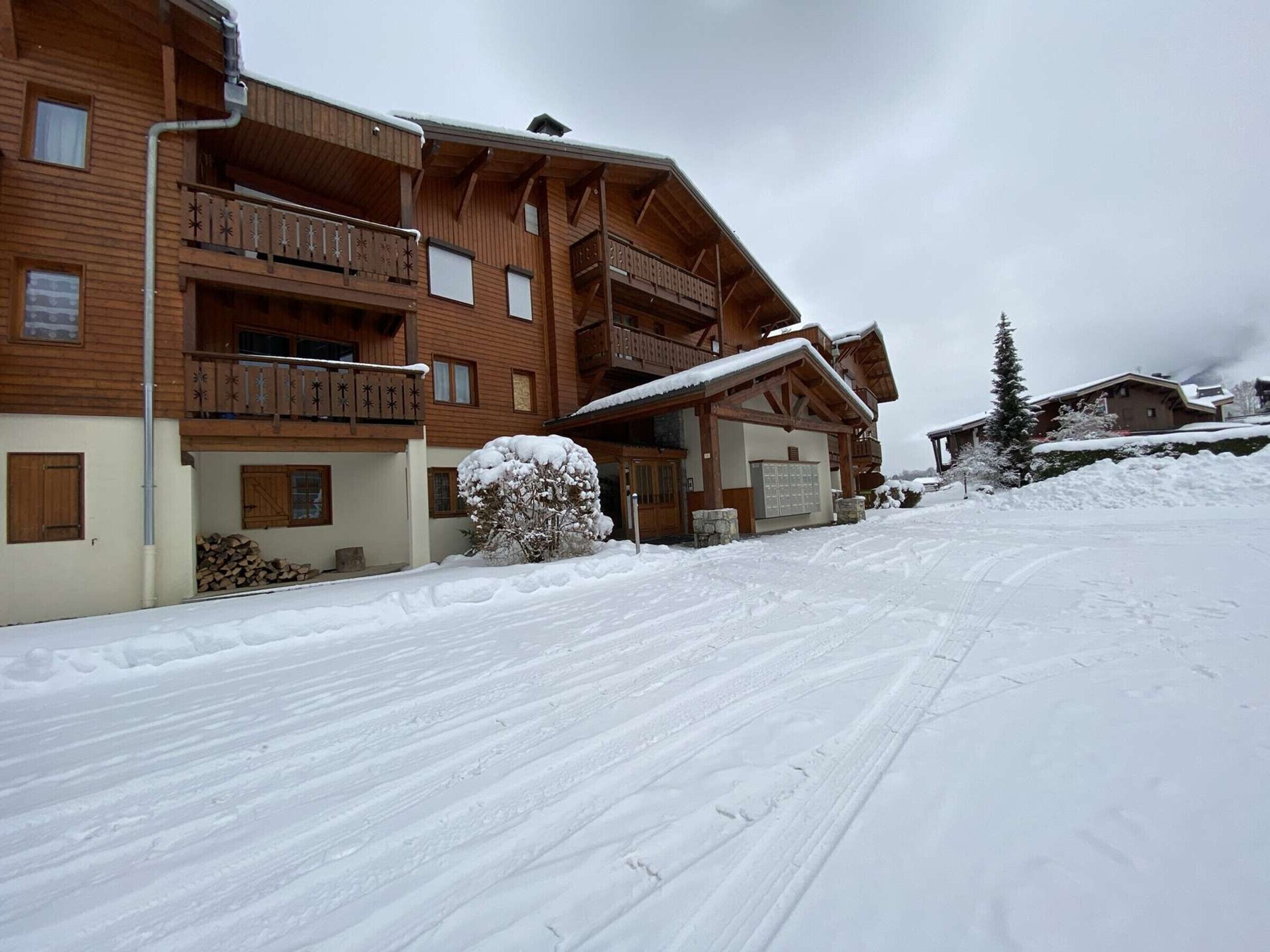 A wooden chalet with balconies, a covered entrance, and a snow-covered driveway.
