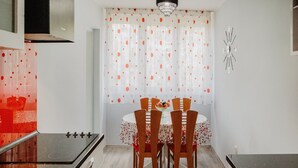 A compact kitchen with a dining area, featuring a stove, cabinets, and a table with chairs. - Apartment Nostalgija Split (Split)