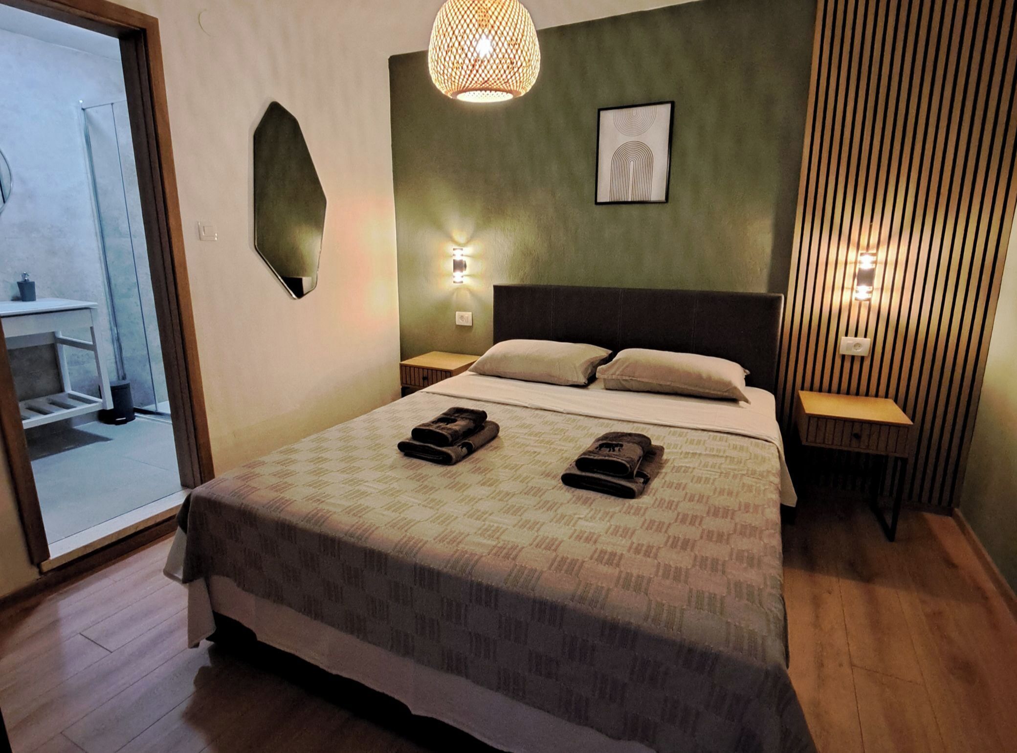 Une chambre d’hôtel avec un lit, deux lampes de chevet, une œuvre d’art accrochée au mur et un miroir.